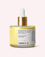 A bottle of Truly Beauty Pineapple Glow Brighten + Exfoliate Face Serum featuring a gold dropper cap, clear yellow liquid, and a white label with black product details, formulated with Pineapple Extract to exfoliate and refine pores for a radiant complexion.