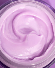 A close-up of a jar filled with Truly Beauty’s Glazed Donut After Shave Glow Cream in light purple, highlighting its smooth, creamy texture and beautiful swirl on top.