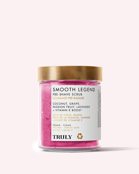 The Smooth Legend Pre-Shave Scrub by Truly Beauty comes in a pink jar with a gold lid and white label, featuring clean, vegan ingredients like coconut, grape, passion fruit, lavender, and Vitamin E for glowing skin.