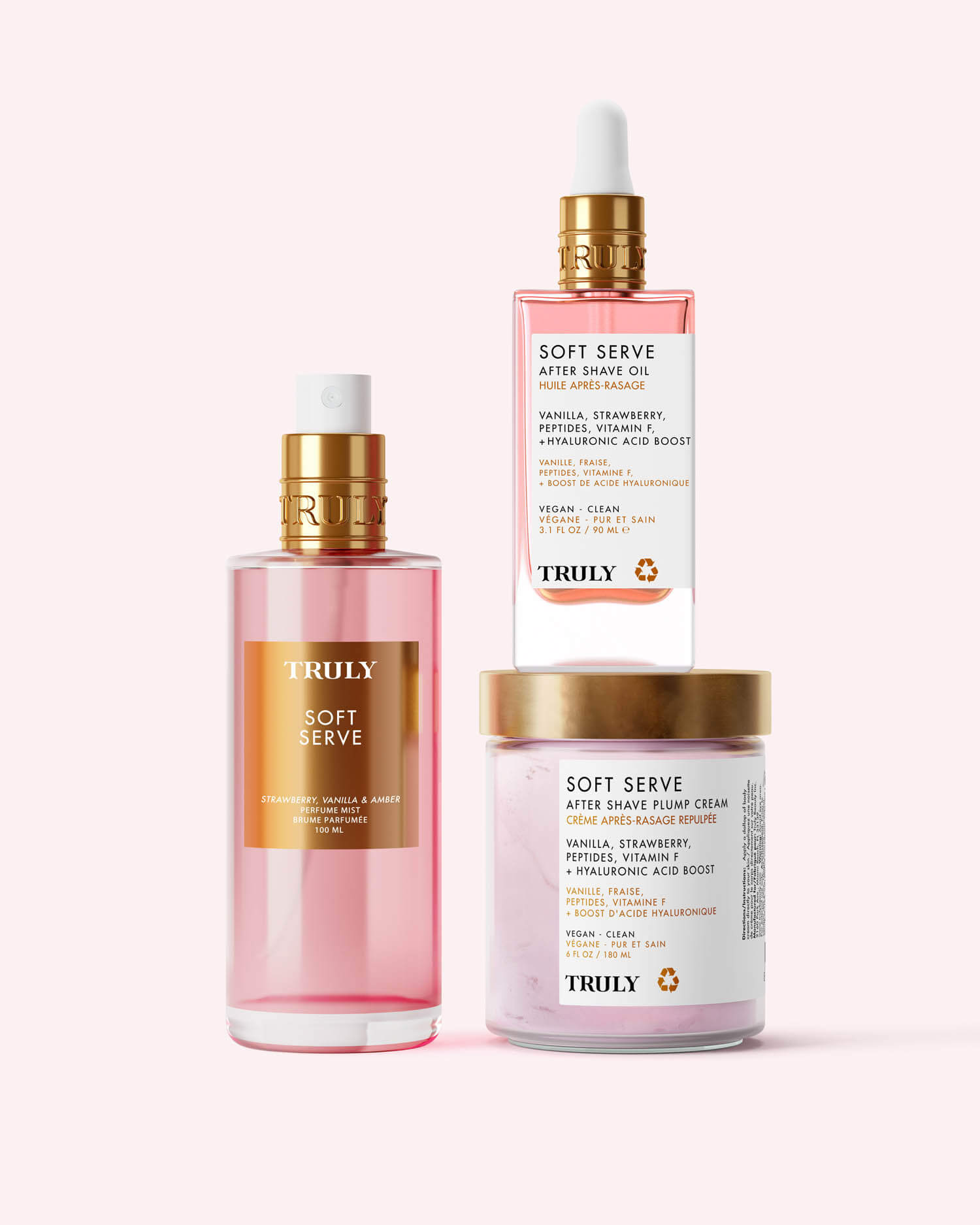 A clear pink bottle of Truly Beauty Soft Serve Perfume Mist with a gold label and cap, boasting a sweet strawberries and cream scent, is photographed against a light pink background.