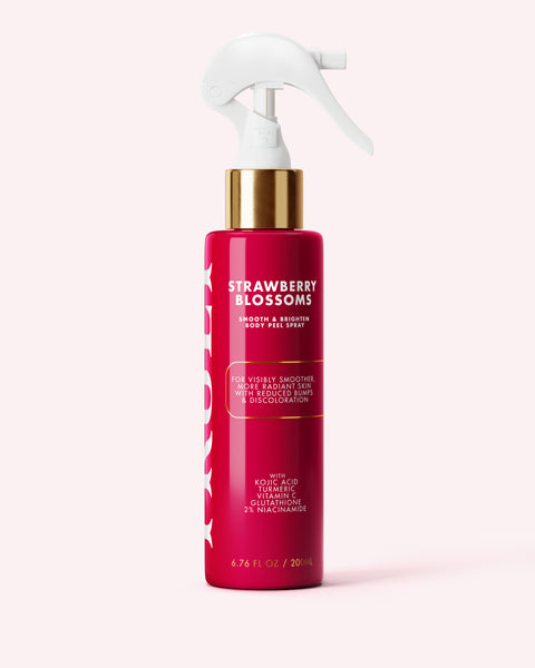 A red spray bottle labeled “Strawberry Blossom Smooth & Brighten Body Peel Spray” by Truly Beauty, featuring gold and white accents, sits on a light pink background. The label highlights benefits such as smoother skin, reducing dark spots, and targeting keratosis pilaris with kojic acid.