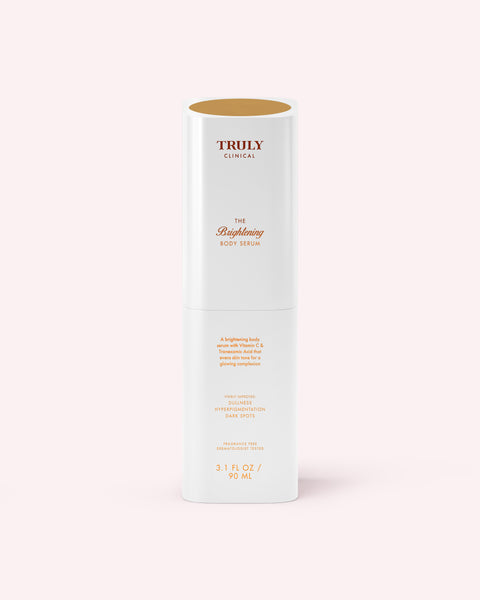 A white cylindrical bottle labeled Truly Beauty The Brightening Body Serum (3.1 fl oz/90 mL), designed to target dark spots and hyperpigmentation, stands upright against a pale pink background with gold and pink text.