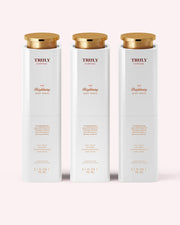 Three white bottles of Truly Beauty’s The Brightening Body Serum with gold caps stand upright in a row against a light pink background. Each 3.1 fl oz (90 mL) bottle targets dark spots and hyperpigmentation for radiant skin.