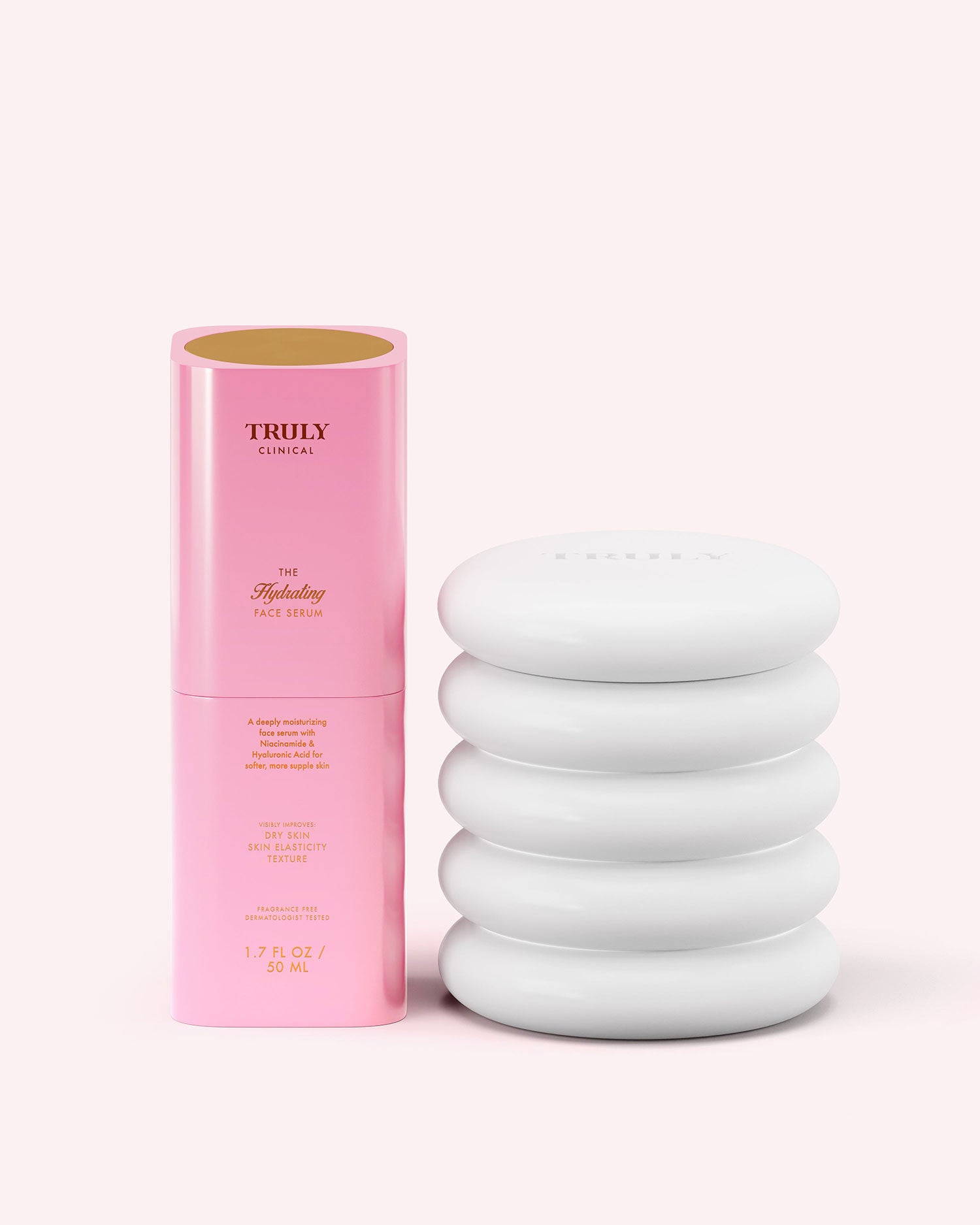 A pink cylindrical bottle labeled Truly Beauty The Hydrating Face Routine stands beside a smooth, white, stackable stone on a pale pink background.
