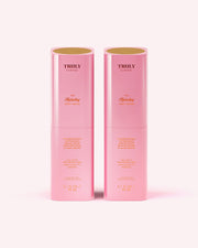 Two pink cylindrical bottles of Truly Beauty’s The Hydrating Body Serum, each labeled 3.1 fl oz (90 mL), stand upright side by side on a light pink background.