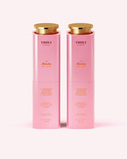 Two pink cylindrical bottles of Truly Beauty's The Hydrating Body Serum with gold caps, featuring niacinamide for hydration. Each has product details in gold and white text on a light pink label.