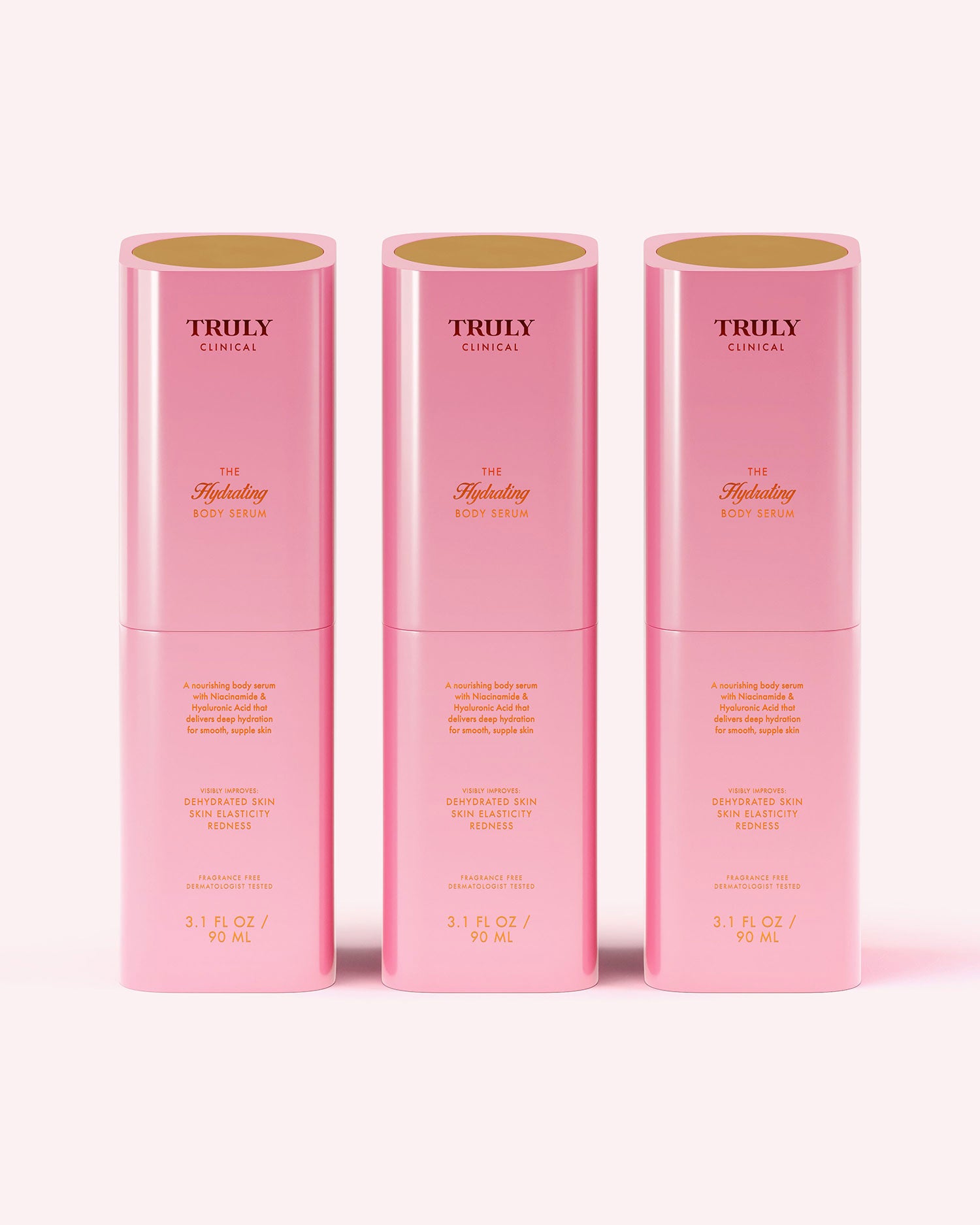 Three pink cylindrical bottles of Truly Beauty The Hydrating Body Serum, each with gold text, stand upright on a light pink background. Each hydrating serum contains hyaluronic acid and 3.1 fl oz (90 ml) of product.