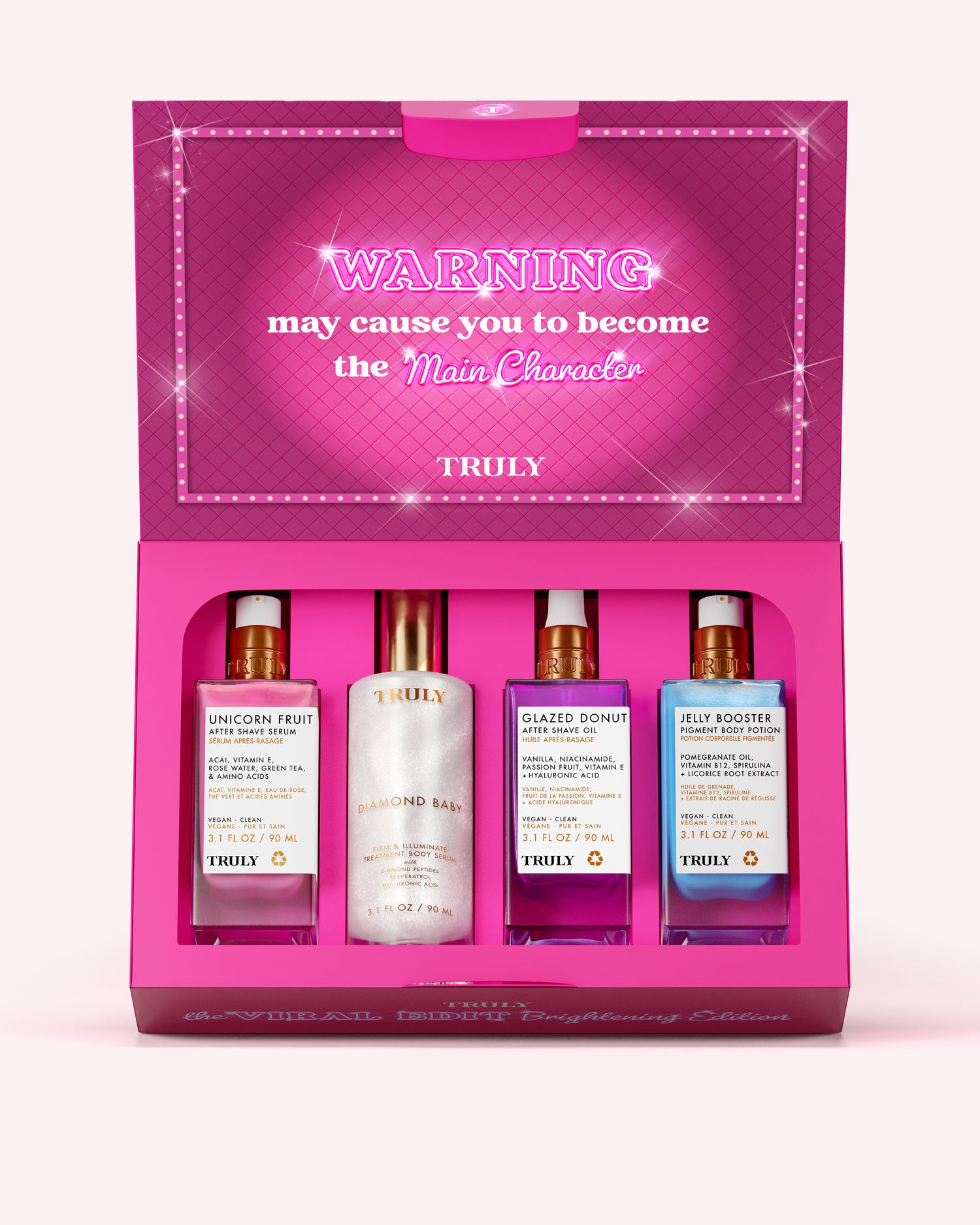 A boxed fragrance gift set from TRULY on a light pink background. The open magenta box contains four bottles: a pink 'Unicorn Fruit' cologne, a white 'Diamond Ring' cologne, a purple 'Glazed Bonbon' cologne, and a blue 'Blue Rose' cologne.