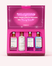 A boxed fragrance gift set from TRULY on a light pink background. The open magenta box contains four bottles: a pink 'Unicorn Fruit' cologne, a white 'Diamond Ring' cologne, a purple 'Glazed Bonbon' cologne, and a blue 'Blue Rose' cologne.