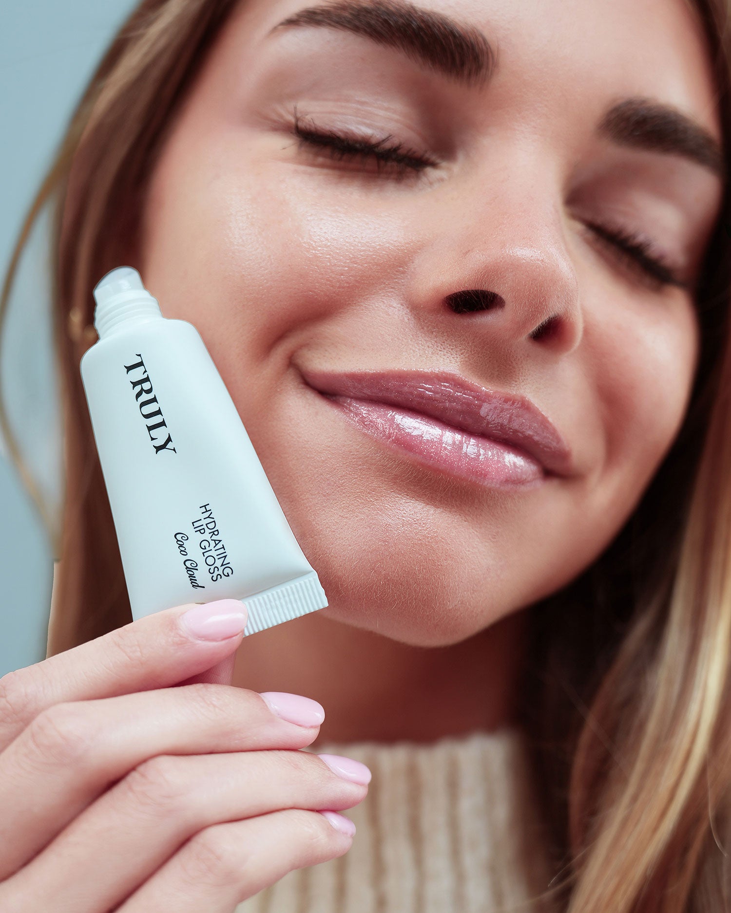 Woman holding a TRUAX skincare product close to her face