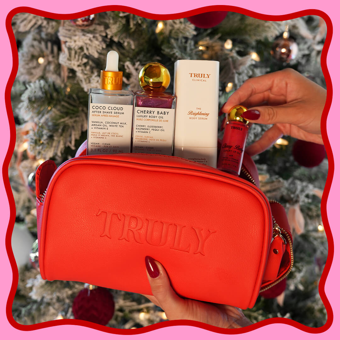 Red 'Truly' cosmetic bag with skincare products against a Christmas tree background