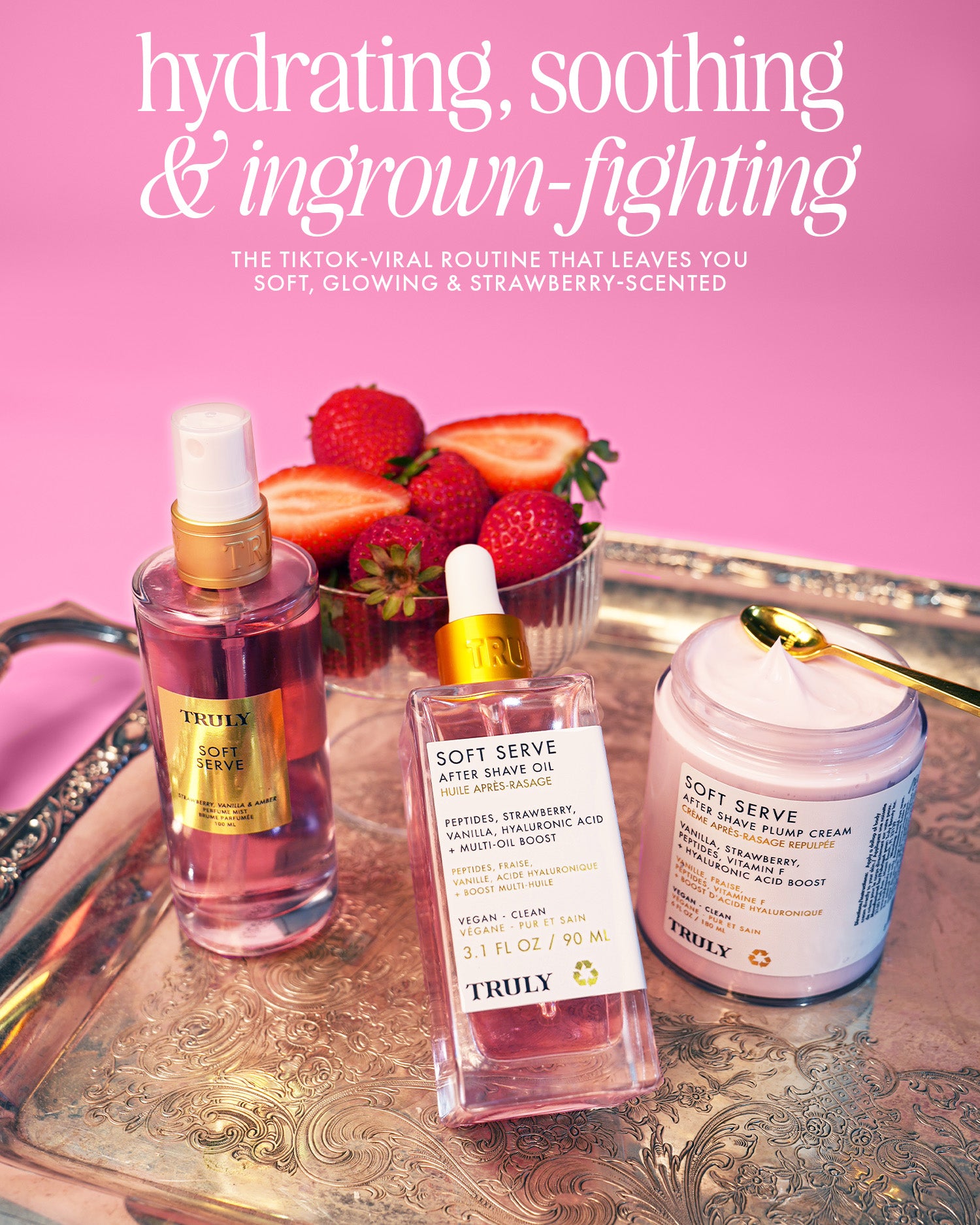 Three Truly Beauty Soft Serve Luxury Trio products on a silver tray with fresh strawberries; text highlights this hydrating, soothing bundle’s ingrown hair care. The pink background enhances the strawberry-scented after shave feel.