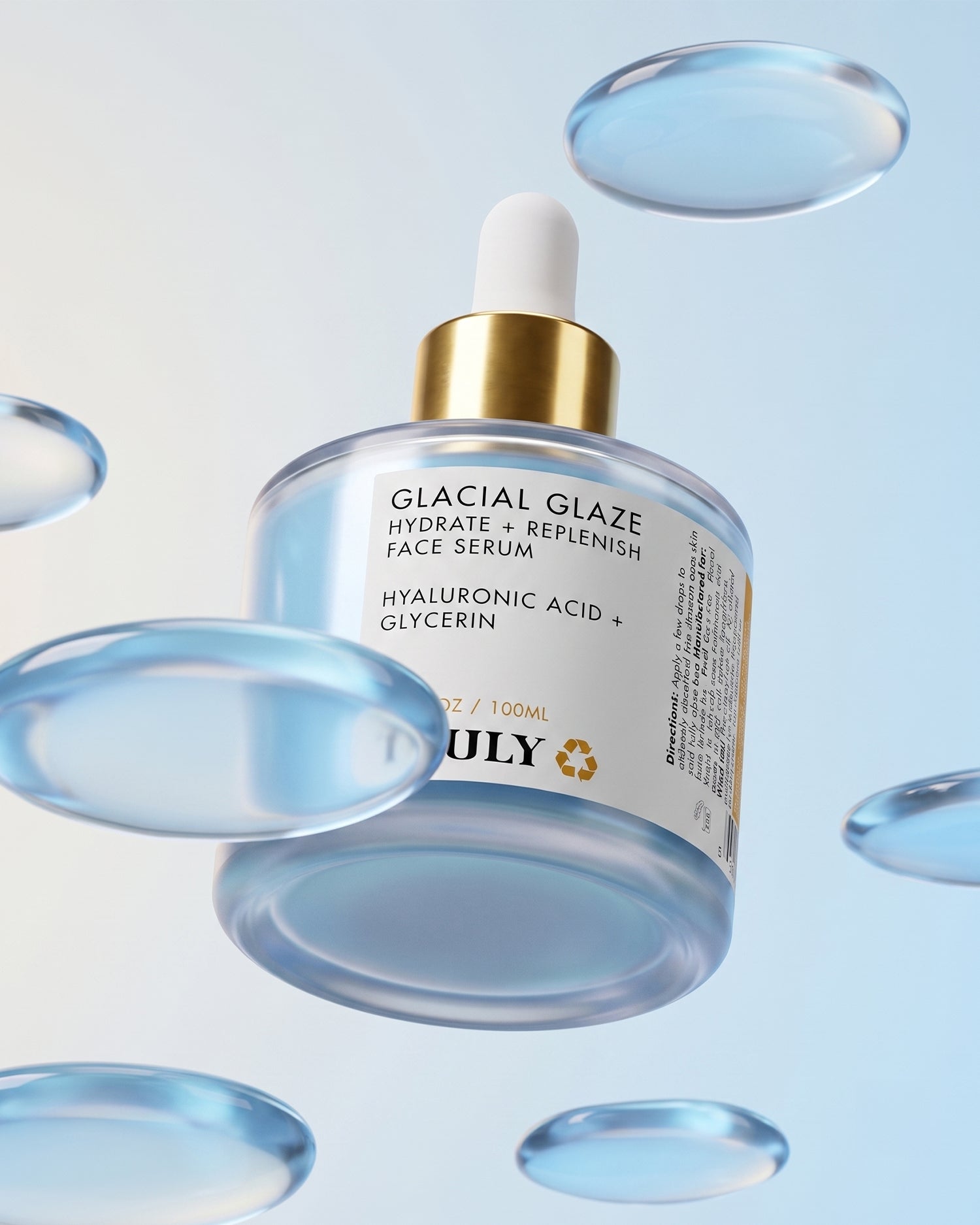 A bottle of Truly Beauty’s Glacial Glaze Hydrate + Replenish Face Serum, complete with a dropper, floats amidst translucent blue droplets on a light blue backdrop. The label showcases hyaluronic acid and glycerin, highlighting the serum’s intensely hydrating formula designed to enhance skin elasticity for a fresh, supple complexion.