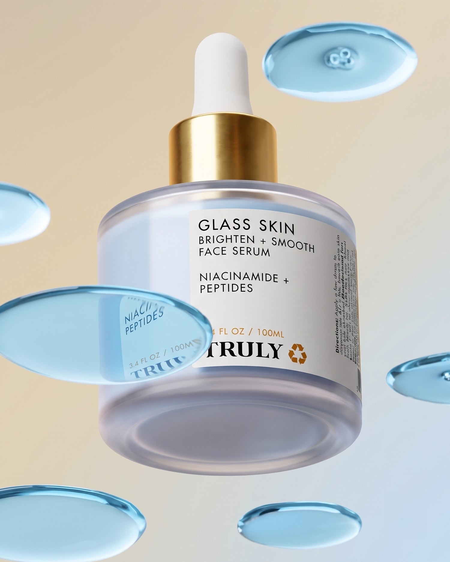 A bottle of Truly Beauty’s Glass Skin Brighten + Smooth Face Serum with a dropper cap floats among blue serum drops against a light gradient background. The label highlights niacinamide and peptides as key ingredients, showcasing this face serum’s ability to deeply hydrate and rejuvenate your complexion.
