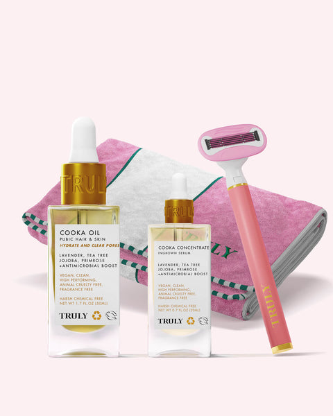 Two bottles of Truly Beautys Ultimate Cooka Treatment are displayed with a folded towel featuring pink edges and a signature razor, all set against a clean white background.