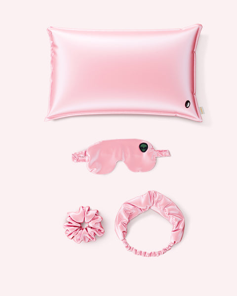 The Truly Beauty Bonne Nuit Beaute Satin Sleep Set in soft pink includes a pillowcase, eye mask, scrunchie, and headband—ideal for enhancing your beauty sleep routine.