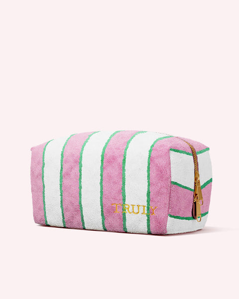 The Truly Pink Terry Stripe Bag by Truly Beauty is a rectangular pouch with pink, white, and green vertical stripes, a zipper on one end, and TRULY embroidered in yellow on soft terry fabric.