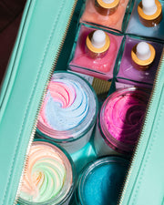 The Signature Vanity Case by Truly Beauty is a teal vegan leather skincare travel pouch, neatly organizing colorful jars of whipped creams and scrubs plus square pastel dropper nail polishes—perfect for your grooming essentials.